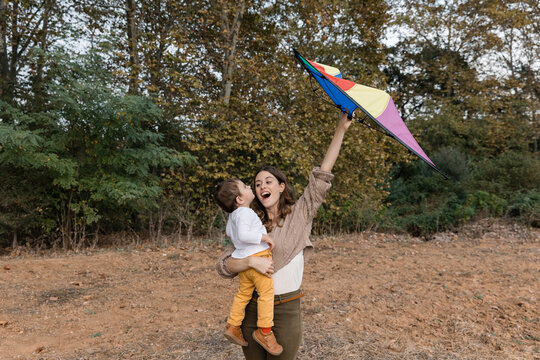 Mother and son playing with kite in autumn park