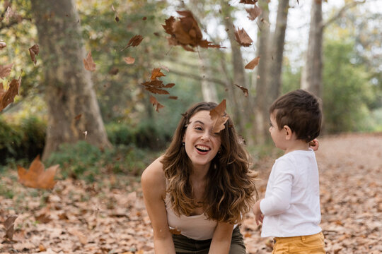 Mother and child playing with autumn leaves