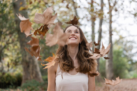 Woman enjoying falling autumn leaves in park