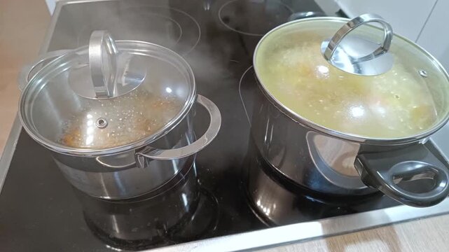 Boiling pots on ceramic cooktop with glass lids shows meal preparation at home with european man checking boiling pots lid with steam and delicious vegetables as healthy meal cooking at home.