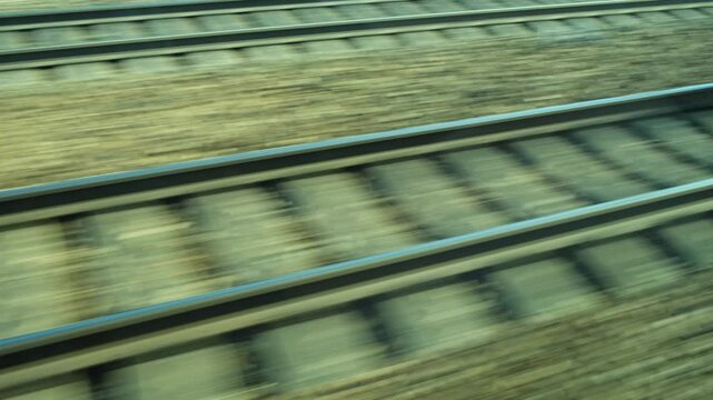 View of railroad tracks and motion blur ground from moving train