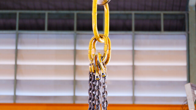 Lifting hooks and chains used in the production process. The hooks are suspended from chains above the work area and are used for lifting and moving heavy workpieces or materials.
