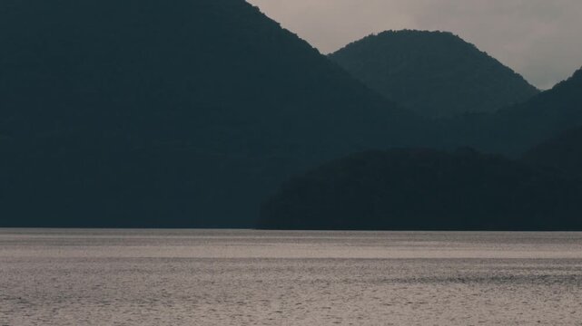 Gray ripples on Lake Toya with a dark blue island silhouette
