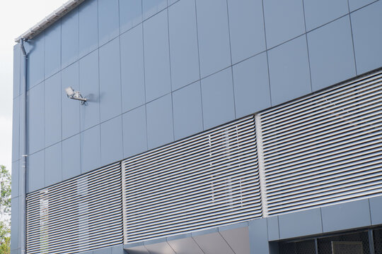 Modern Industrial Building Facade with Blue Metal Cladding Panels, CCTV Camera, and Exterior Wall Structure