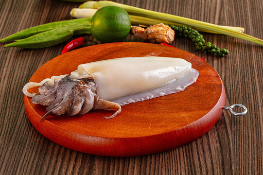 Fresh cuttlefish on wooden cutting board with lime lemongrass and chili