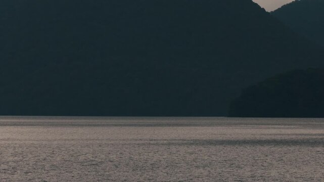 Gray ripples on Lake Toya with a dark blue island silhouette
