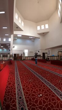 Panning interior view of Ijabah Mosque showcasing its spacious prayer hall and red carpet.