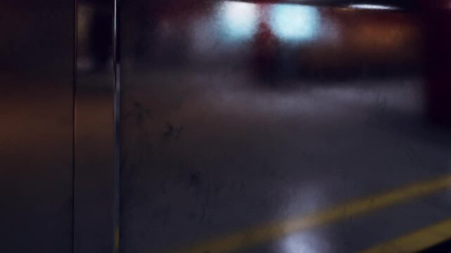 A round button is shown on a shiny metallic surface. The location appears to be a parking area with a blurred background. The time seems to be in the evening as the light is low.