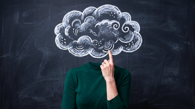Woman pointing finger up under a chalk cloud drawing on a blackboard representing her thoughts.