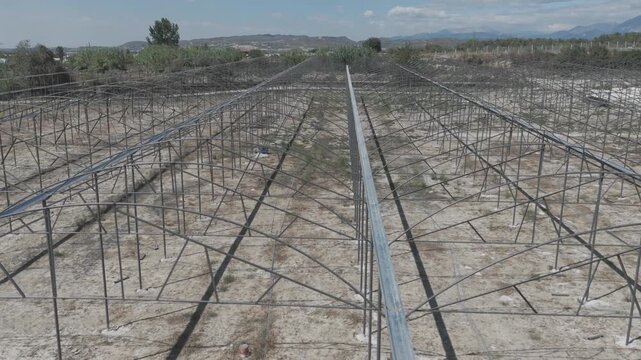 Aerial drone flight over the metal skeleton framework of a greenhouse under construction. [D-Log M]