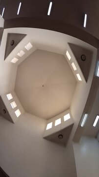 Low angle view looking up at the geometric white ceiling and windows of Ijabah Mosque.