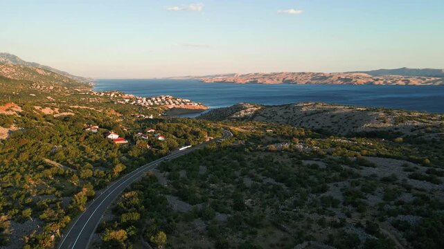 Car driving along coastal road near sea and small village, aerial view