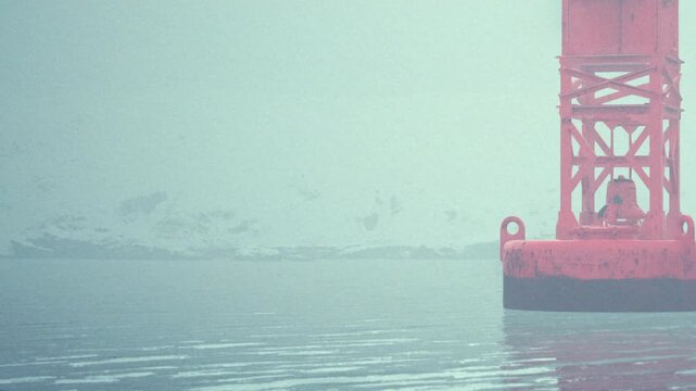 The bright buoy floats in still water surrounded by snow covered mountains. The scene shows a cloudy sky and a peaceful landscape.