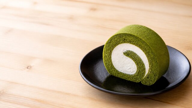 黒漆の皿に盛った秋の抹茶ロールケーキ 緑の生地と白いクリームの和スイーツ