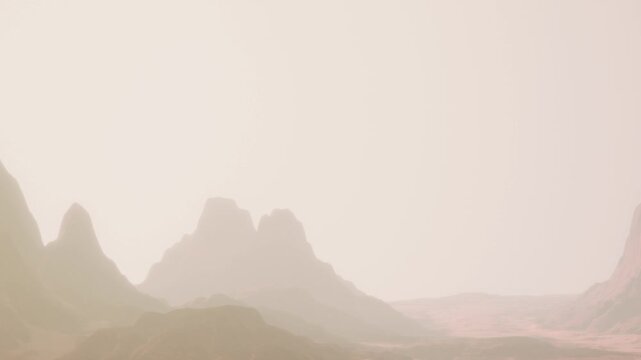 Distant mountains rise above a rocky terrain during early morning hours. The soft light creates a hazy atmosphere, highlighting the natural shapes of the landscape.