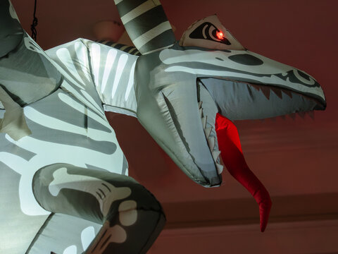 A glowing inflatable skeleton dragon with bright red eyes decorates a front porch for Halloween. The dramatic close-up highlights the creature's fierce appearance.