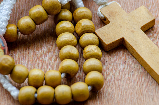 Close up view of wooden Holy Rosary on wooden table with customizable space for text. Religion concept.