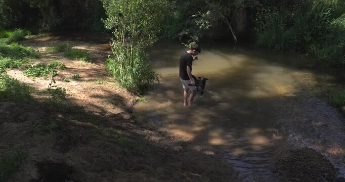 Young man playing with his dog in the river