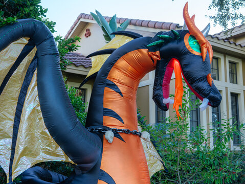 A detailed view of a giant inflatable dragon with glowing eyes and dramatic wings displayed outside a home. The festive Halloween decoration adds excitement to the neighborhood.