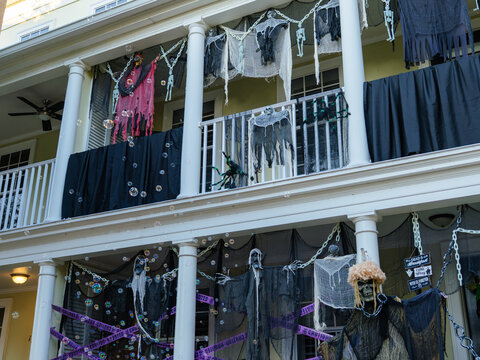 A multi-story home is transformed with ghosts, skeletons, chains, and spooky Halloween decorations. The elaborate display creates a haunted house atmosphere for the holiday season.