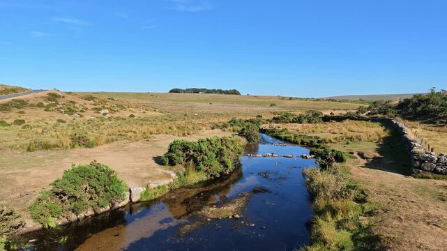 Dartmoor Devon England UK. 13.08.2026. Video. A tranquil rural scene on Dartmoor unfolds with a clear blue sky above the west River Dart and a rustic stone boundary wall
