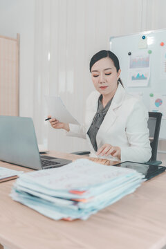 Asian Businesswoman Working on Laptop and Taking Notes at Desk in Office