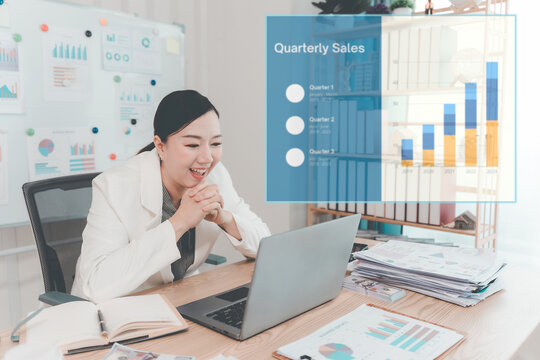 Asian Businesswoman Working on Laptop and Taking Notes at Desk in Office