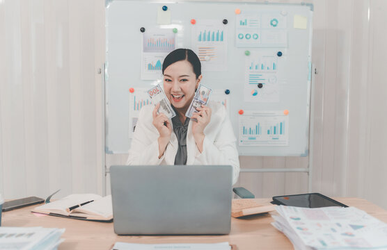 Cheerful Asian Businesswoman Celebrating Success looking at Laptop Screen in Office