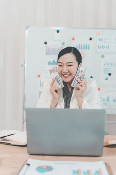 Cheerful Asian Businesswoman Celebrating Success looking at Laptop Screen in Office