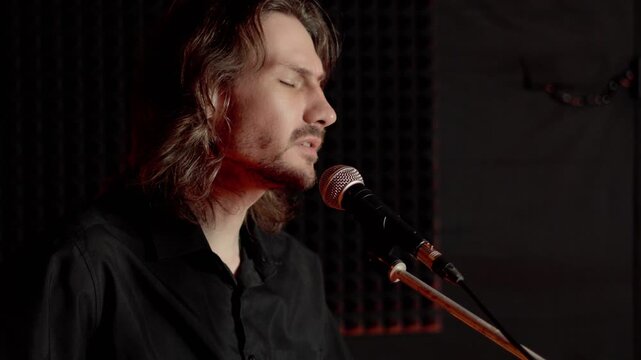 A guy in a black shirt is singing into the microphone.