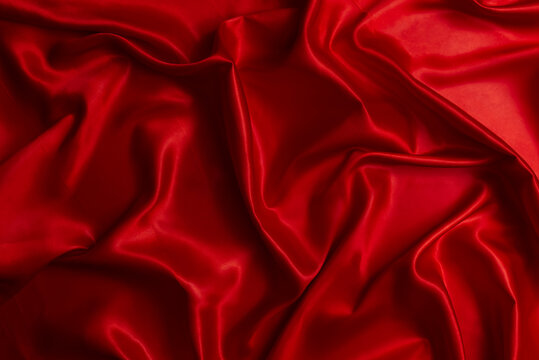 A beautiful, rippling red satin fabric surface.