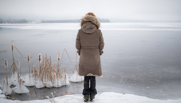 Person Looking Out Across Frozen Lake in Winter Coat