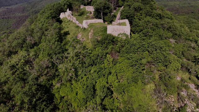 Drone aerial of the medieval ruins of Sz&aacute;dv&aacute;r Castle near Sz&ouml;gliget, Hungary, overlooking the forested Aggtelek Hills and surrounding countryside.