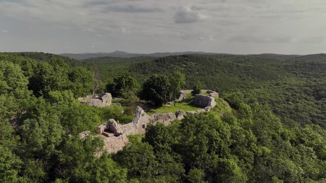 Drone aerial of the medieval ruins of Sz&aacute;dv&aacute;r Castle near Sz&ouml;gliget, Hungary, overlooking the forested Aggtelek Hills and surrounding countryside.