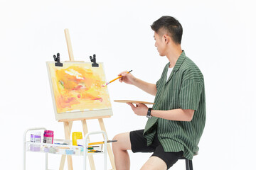 Young man painting abstract canvas at easel in bright studio © DaoYenThu