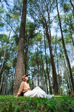 Vertical portrait image of a woman sitting and relaxing in the park