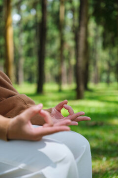 Vertical closeup of a woman meditating or practicing yoga in lotus pose in the park