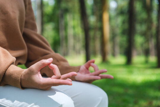 Closeup of a woman meditating or practicing yoga in lotus pose in the park