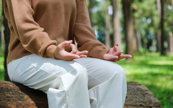 Closeup of a woman meditating or practicing yoga in lotus pose in the park