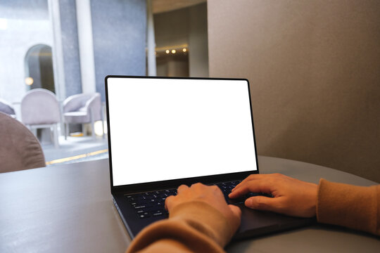 Mockup image of a woman working and typing on laptop computer with blank white desktop screen in cafe