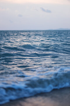 Vertical landscape image of sea wave splashing on beach before sunset