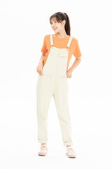 Fototapeta premium Smiling young woman wearing light overalls and orange t-shirt in studio