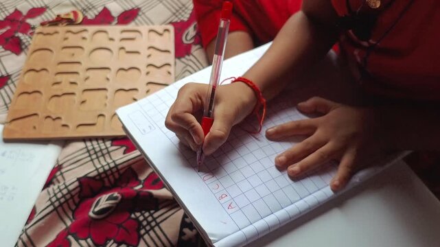 Child Writing English Alphabets and Numbers in Notebook for Home Education