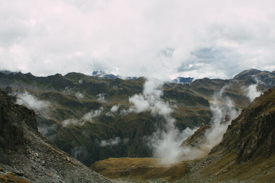Dramatische alpine Berglandschaft mit tief ziehenden Wolken zwischen felsigen Hochgebirgsh&auml;ngen
