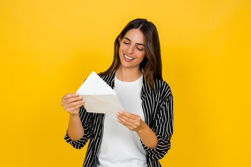 Woman smiling with closed eyes, holding an open envelope with a letter or important message inside,...
