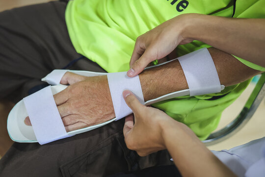 Therapist making assistive device for immobilize patient hand. Splint service for hand injury rehabilitation of occupational therapy clinic.