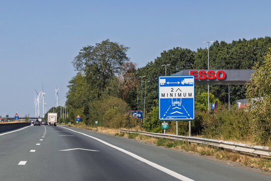 Belgium, 14 August 2026. Blue highway sign indicating minimum two chevron distance for trucks on a Belgian motorway near gas station.