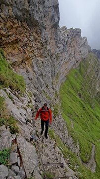 Experience the breathtaking journey as a hiker navigates the rocky trails of Meglisalp in Appenzell, Switzerland.