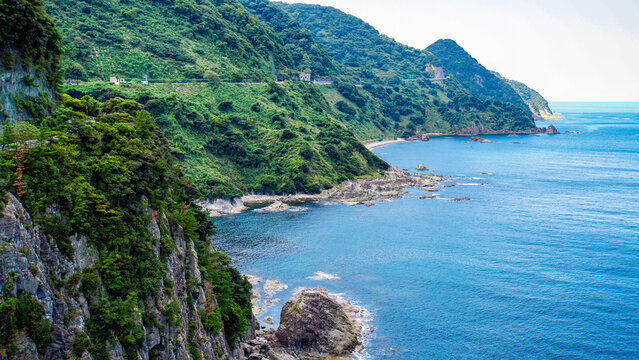 切り立った断崖と深い緑の山肌に沿って広がる青い海岸線
