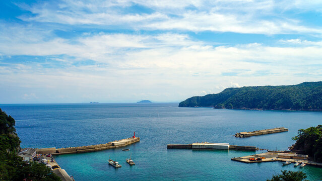 青空と水平線が広がる穏やかな港と防波堤の俯瞰風景